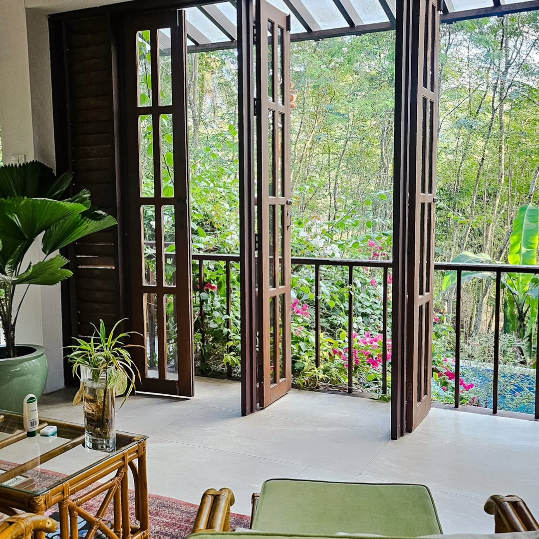 The heritage homestead living area with open wooden doors looking out to the lush garden and pool at The Red Hen Homestead